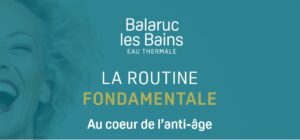 Femme cheveux blancs et rouge à lèvres rouge qui sourie à pleine dent sur fond bleu canard aux couleurs de la marque Balaruc-les-Bains Eau thermale, logo de la marque et texte descriptif : la routine fondamentale, au cœur de l'anti-âge